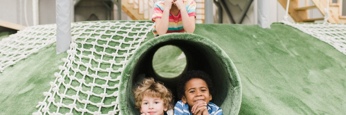 Friendly intercultural little kids having rest on play area at leisure center